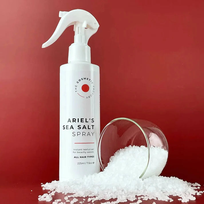 a bottle of ariel's sea salt spray 225ml next to salt.