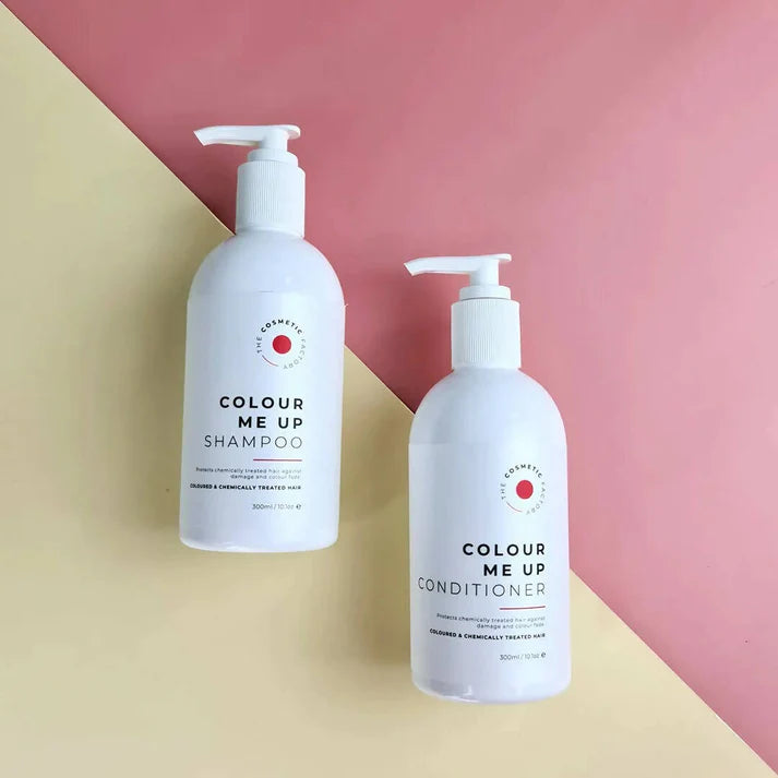 two bottles of colour me up shampoo 300ml on a red surface.