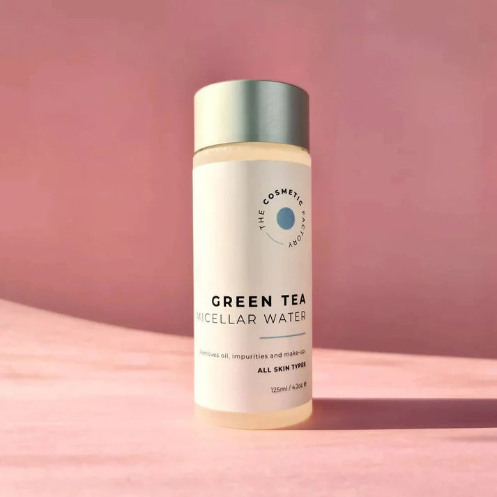 a bottle of green tea micellar water 125ml on a pink surface.