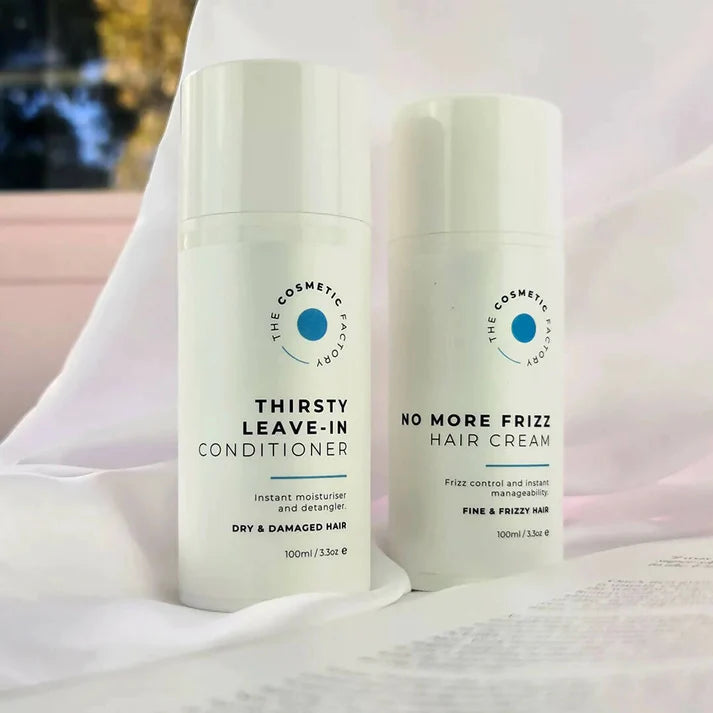 a bottle of no more frizz hair cream 100ml on a blue surface.